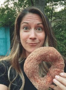 Angela Blue holding a cinnamon doughnut from Klassic Doughnuts